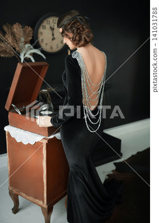 1920s style girl in backless black velvet dress with luxurious back jewelry 1920s style girl in backless black velvet dress with luxurious back jewelry 141031788