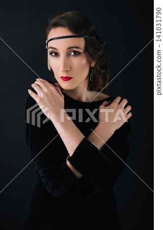 1920s style girl in black velvet dress posing with arms crossed on chest 1920s style girl in black velvet dress posing with arms crossed on chest 141031790