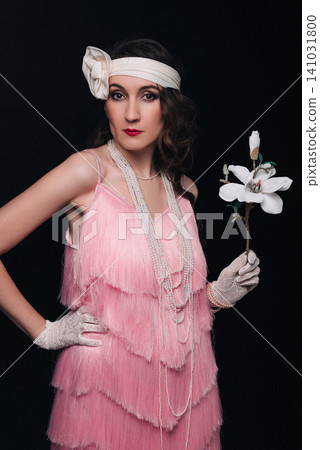 Elegant young woman and girl in 1920s style holding a white magnolia flower Elegant young woman and girl in 1920s style holding a white magnolia flower 141031800