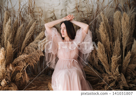 Dreamy young woman and girl in pink tulle dress posing among pampas grass Dreamy young woman and girl in pink tulle dress posing among pampas grass 141031807