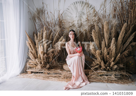 Ethereal young woman and girl in pink dress holding a protea flower among pampas grass Ethereal young woman and girl in pink dress holding a protea flower among pampas grass 141031809