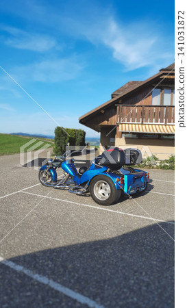 Custom blue motorized trike parked in an alpine setting Custom blue motorized trike parked in an alpine setting 141031872