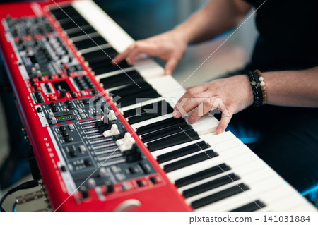 Close-up of musician's hands playing a red professional electronic keyboard synthesizer 141031884