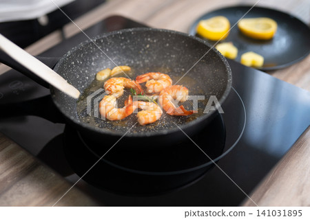 Sizzling shrimp with garlic and fresh herbs in a frying pan Sizzling shrimp with garlic and fresh herbs in a frying pan 141031895