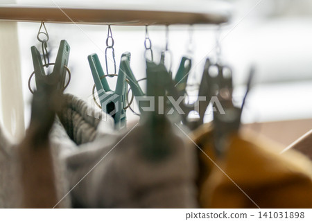 A close-up shot of a corner clothes hanger with a row of mint green clothespins, taken with a shallow depth of field. 141031898
