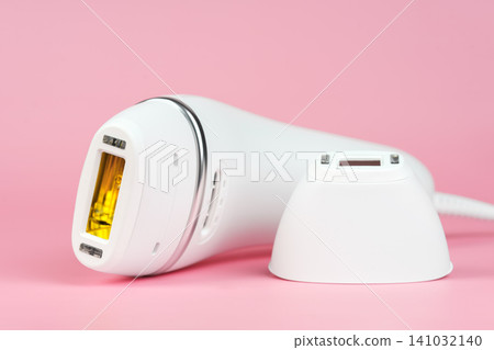 Modern white IPL photoepilator and attachment precision attachment on pink background Modern white IPL photoepilator and attachment precision attachment on pink background 141032140