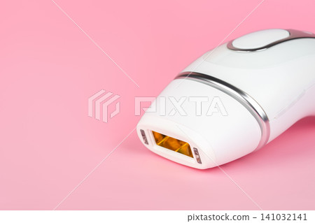 Modern IPL photoepilator isolated on pink background. Modern beauty device for home hair removal Modern IPL photoepilator isolated on pink background. Modern beauty device for home hair removal 141032141