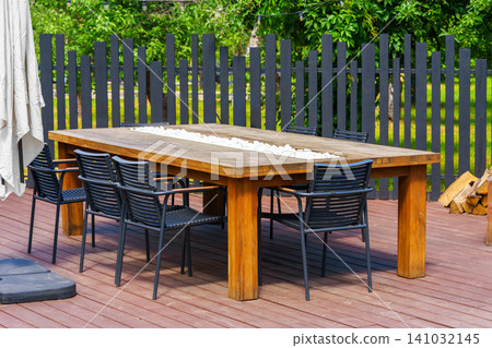 Modern outdoor dining table and chairs on backyard patio terrace, place to relax for group of people 141032145