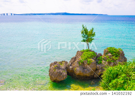 美麗的宮古藍海,宮古島的伊良部橋,以及神秘的岩石海岸,背景是伊良部島,周圍環繞著樹木和植物(沖繩縣宮古島) 美麗的宮古藍海,宮古島的伊良部橋,以及神秘的岩石海岸,背景是伊良部島,周圍環繞著樹木和植物(沖繩縣宮古島) 141032192