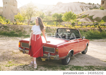 beautiful happy girl in a skirt posing near a retro car in the mountains of cappadocia beautiful happy girl in a skirt posing near a retro car in the mountains of cappadocia 141032232