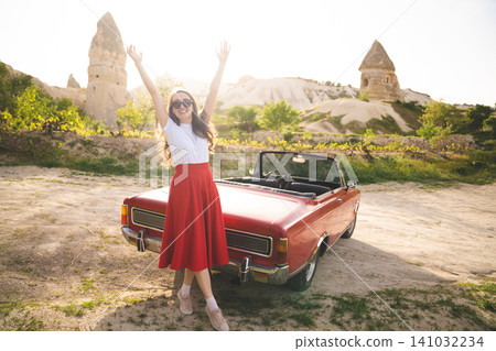 beautiful happy girl in a skirt posing near a retro car in the mountains of cappadocia beautiful happy girl in a skirt posing near a retro car in the mountains of cappadocia 141032234