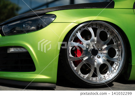 Close-up of lime green tuned sport car with custom deep dish rims Close-up of lime green tuned sport car with custom deep dish rims 141032299