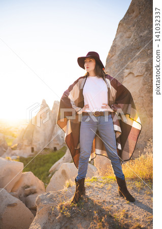 girl hiker in poncho and hat on top of mountain at sunset girl hiker in poncho and hat on top of mountain at sunset 141032337