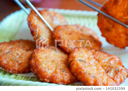 Korean traditional mung bean pancakes Bindaetteok being picked up with chopsticks Korean traditional mung bean pancakes Bindaetteok being picked up with chopsticks 141032399