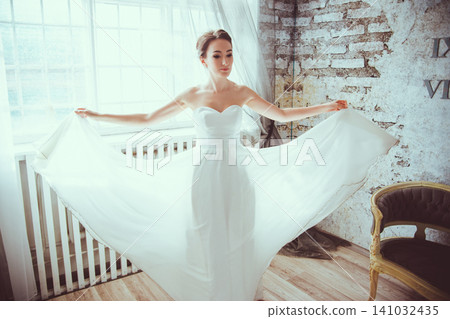 Young girl in white dress spinning and dancing in classic vintage interior 141032435