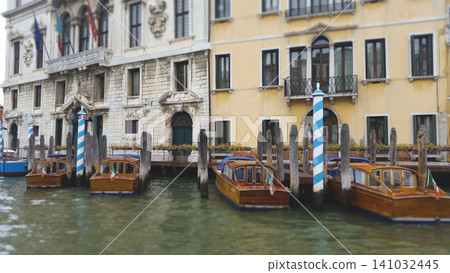 Traditional wooden water taxis moored along the Grand Canal near historic Venetian palaces in Italy Traditional wooden water taxis moored along the Grand Canal near historic Venetian palaces in Italy 141032445