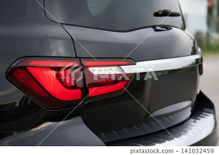 Close-up of a black luxury SUV rear LED taillight and chrome tailgate trim Close-up of a black luxury SUV rear LED taillight and chrome tailgate trim 141032459