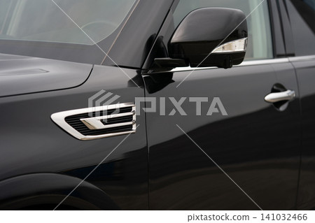 Close-up side view of a black luxury SUV showing fender vent and side mirror Close-up side view of a black luxury SUV showing fender vent and side mirror 141032466