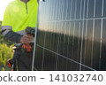 A worker installs a solar panel. 141032740