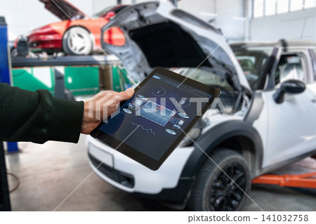 Checking the battery pack of an electric car at a service center. Checking the battery pack of an electric car at a service center. 141032758