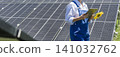 Female farmer with digital tablet on a modern farm using solar panels. Agricultural silos in the background.. 141032762