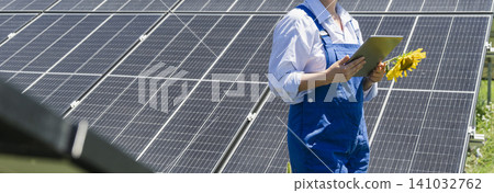 Female farmer with digital tablet on a modern farm using solar panels. Agricultural silos in the background.. Female farmer with digital tablet on a modern farm using solar panels. Agricultural silos in the background.. 141032762