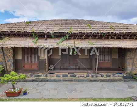 Traditional Korean Thatched House with Loofah Vines Hanging from Eaves Traditional Korean Thatched House with Loofah Vines Hanging from Eaves 141032771