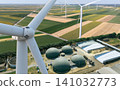 Green energy synergy. Close-up of wind turbine with biogas plant infrastructure in the background 141032773