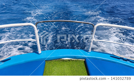View from the stern of a boat with foamy wake across deep blue sea, capturing the feeling of marine travel, adventure, and a sunny summer voyage on open water. View from the stern of a boat with foamy wake across deep blue sea, capturing the feeling of marine travel, adventure, and a sunny summer voyage on open water. 141032789