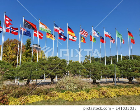 International National Flags Waving on Poles Against Blue Sky International National Flags Waving on Poles Against Blue Sky 141033035