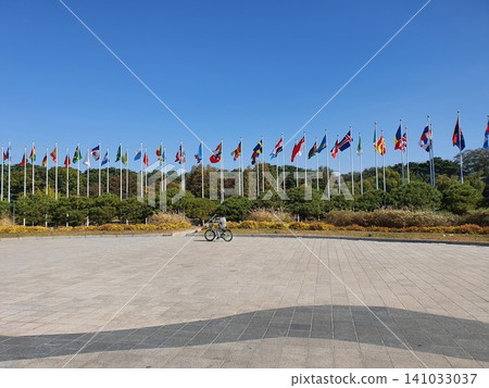 International National Flags Waving on Poles Against Blue Sky 141033037
