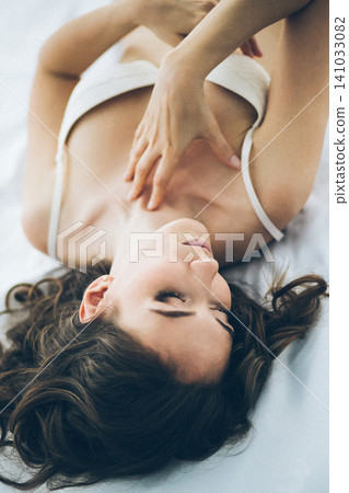 Beautiful and sensual young girl in white lingerie relaxing on bed Beautiful and sensual young girl in white lingerie relaxing on bed 141033082