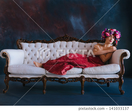 Sensual woman in flower wreath posing topless on vintage sofa Sensual woman in flower wreath posing topless on vintage sofa 141033137