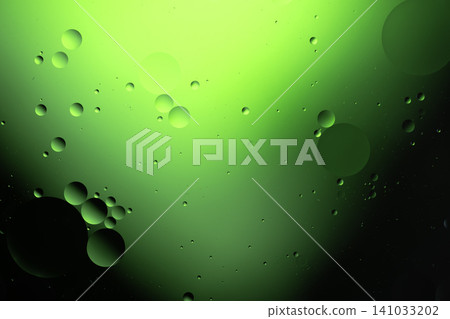Oil droplets floating in water creating a vibrant green abstract background texture Oil droplets floating in water creating a vibrant green abstract background texture 141033202