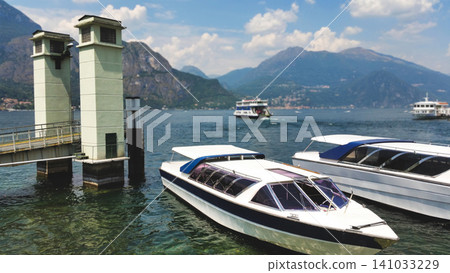 Scenic view of Lake Como with passenger ferry boats and historic villas on mountain slopes 141033229