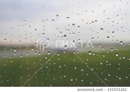 Raindrops on a window with a blurred view of an airfield 141033262