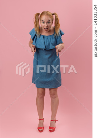 Woman with red pigtails and denim dress expressing surprise and pointing down, directing attention to content or information Woman with red pigtails and denim dress expressing surprise and pointing down, directing attention to content or information 141033354