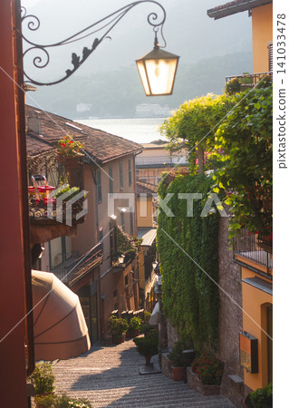 Picturesque narrow street with stone steps and an ornate street lamp in Bellagio on Lake Como 141033478