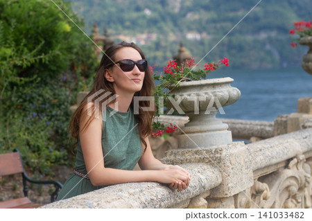 Woman in sunglasses enjoying the view on a stone terrace in Italy Woman in sunglasses enjoying the view on a stone terrace in Italy 141033482