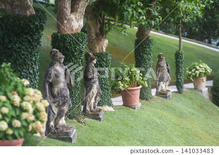 Classical garden sculptures and ivy-covered trees at Villa del Balbianello on Lake Como 141033483