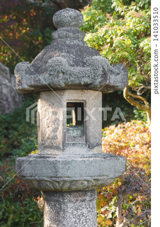 Traditional stone lantern standing amongst lush greenery in a peaceful Japanese garden 141033510