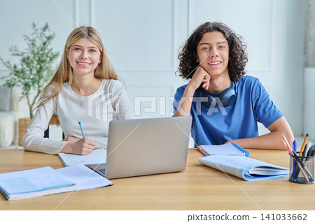 Two smiling teen students with laptop at desk Two smiling teen students with laptop at desk 141033662