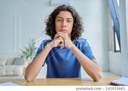 Serious teen boy listening during online lesson Serious teen boy listening during online lesson 141033663