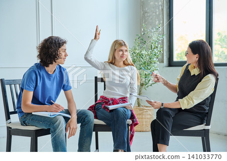 Teenage girl raising hand during youth group session Teenage girl raising hand during youth group session 141033770