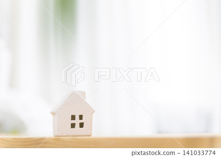 一間光線明亮的房間裡，桌上擺放著一棟微型房屋（我的家/住宅），並留有文字空間。 141033774