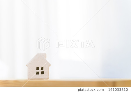 A miniature house (my home/residential) placed on a table in a brightly lit room, with copy space. A miniature house (my home/residential) placed on a table in a brightly lit room, with copy space. 141033810