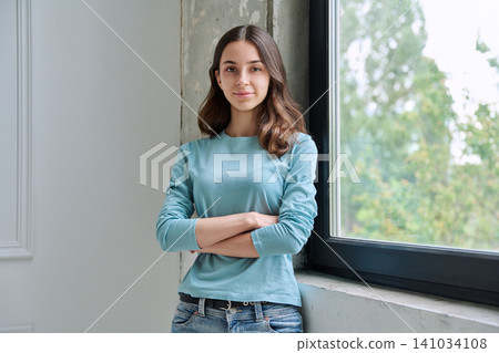 Calm teen girl with crossed arms looking at camera Calm teen girl with crossed arms looking at camera 141034108