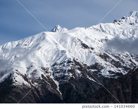 The picture shows a majestic mountain range covered with a thick layer of snow 141034660