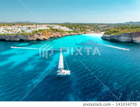 Aerial view of sailing catamaran yacht in turquoise sea water bay Aerial view of sailing catamaran yacht in turquoise sea water bay 141034770