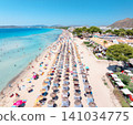 Aerial view of Alcudia sandy beach resort in Mallorca, Spain. Shore with straw umbrellas and sunbeds, crowd of tourists swimming in turquoise sea water. Top drone view. Summer tropical landscape 141034775